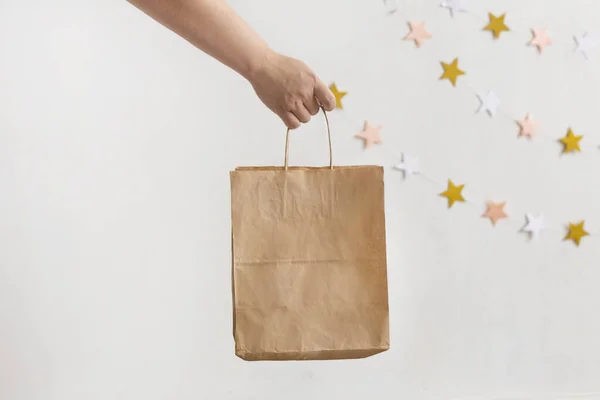 Beyaz bir arka planda kahverengi şeffaf bir kağıt torbayı elinde tutan bir kadının fotoğrafını çek. Paketleme şablonu modeli. Teslimat hizmeti konsepti. Kopya için yer var. Reklam alanı