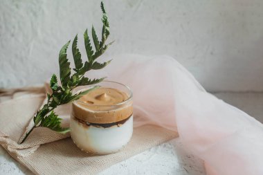 Sütlü buzlu Dalgona kahvesi. Bardakta nefis, soğuk bir içecek. Beyaz arkaplanda bir kopya alanı var.