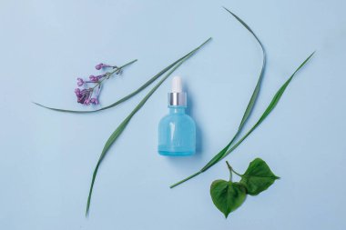 Organik kozmetik ürünleri. Serum açık mavi arkaplanda, üst görünümde. Güzellik rutini konsepti.