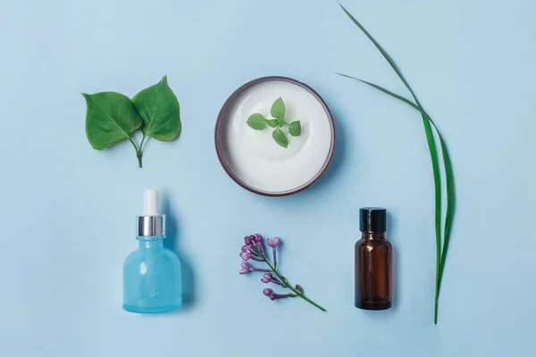 Organik kozmetik: vücut kremi, yüz kremi, açık mavi arka planda serum, üst manzara. Güzellik rutini konsepti.