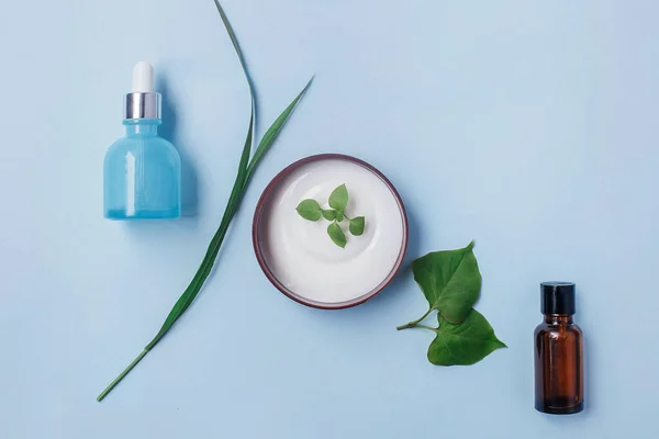 Organik kozmetik: vücut serumu, yüz kremi, açık mavi arka planda serum, üst manzara. Güzellik rutini konsepti.