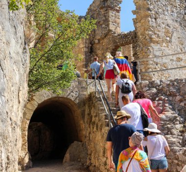 Tatilde olan turistler dağlardaki antik bir şatonun kalıntılarına taş merdivenlerden tırmanırlar, sporcular için aktif bir eğlence.