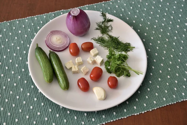 Yeşil masa örtüsü üzerinde sebzeli beyaz tabak..