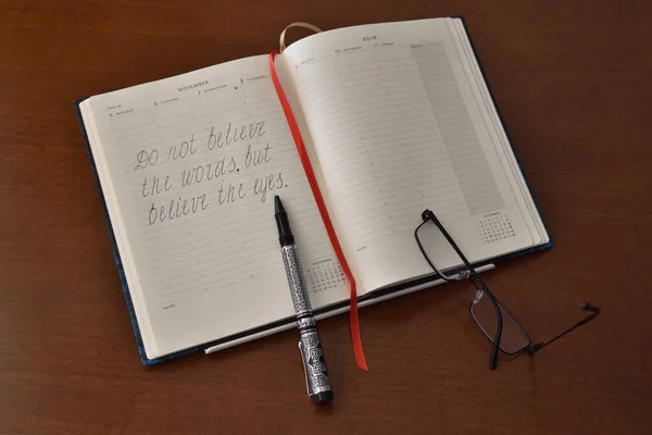 Masanın üzerinde yazılı bir teklif, kalem ve gözlük olan açık bir defter..