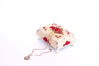 Beyaz arka planda kapalı bir mücevher kutusu. Tabutun üzerinde altın bir zincir ve kolye var.