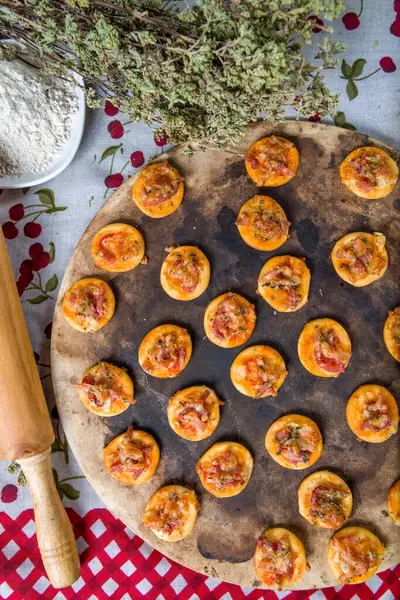 Mutfak malzemeleriyle çevrili mini pizzalar.