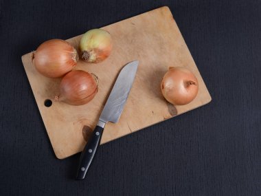 Mutfak tahtasına saplanmış soğanlı siyah arka plan, üst manzara.