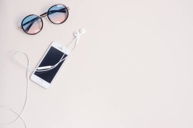 Güneş gözlüğü, telefon ve kulaklık sol taraftaki bej arka planda, plaj için bir yaz şeyi.