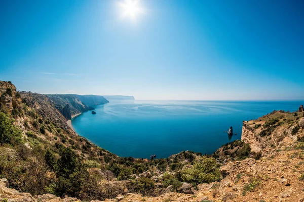 Panoramic seascape, calm azure sea and bright sun. View of the Black Sea coast in Crimea, Cape Fiolent in Sevastopol, Russia. Copy space. Travel, relax or loneliness concept.
