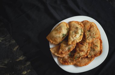 Siyah arka planda beyaz bir tabakta dokuz domuz turtası.