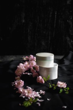 Siyah arka planda pembe çiçekli iki beyaz krema tenceresi.