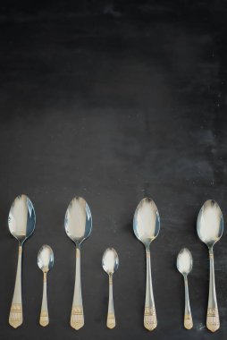 dört güzel büyük gümüş kaşık ve üç küçük kaşık tatlı için siyah arka planda
