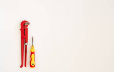 Kırmızı ayarlanabilir anahtarlar beyaz arka planda sarı bir tornavidanın yanında duruyor.