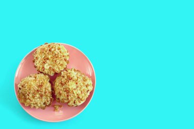 Fıstıklı üç kek mavi arka planda pembe bir tabakta yatıyor.