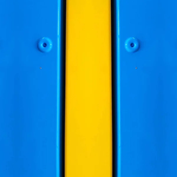 bright blue painted metal with rivets against vivid sunshine yellow background