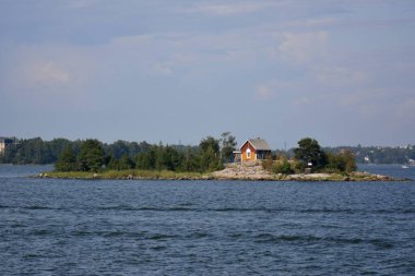 Helsinki, Finlandiya. 24 Temmuz 2014. Helsinki limanında üzerinde ağaçlar ve ahşap kırmızı bir ev olan küçük bir ada..