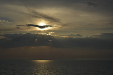 Baltık Denizi. 24 Temmuz 2014. Sakin denizin üzerinde gün batımı, bulutların arasında gizlenmiş güneş..