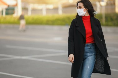 Maskeli bir kız cadde boyunca yürüyor. Coronavirus enfeksiyonu COVID-19