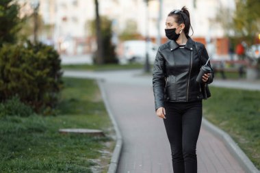 Maskeli bir kız cadde boyunca yürüyor. Coronavirus enfeksiyonu COVID-19