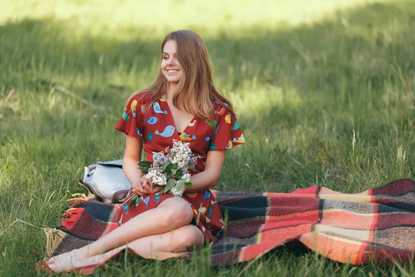 Schöne Mädchen in einem Kleid auf der Natur auf einem Picknick mit Blumen in der Sonne — Stockfoto