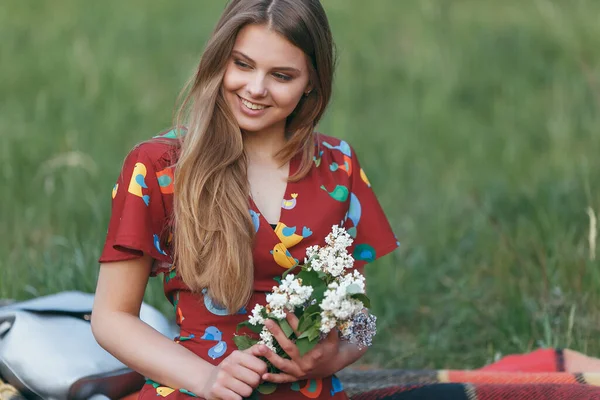 Menina bonita em um vestido na natureza em um piquenique com flores ao sol — Fotografia de Stock