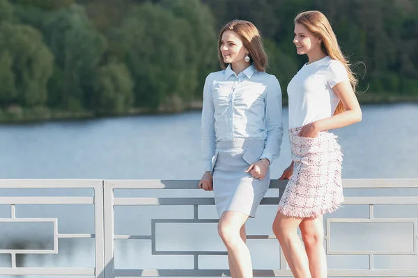 两个年轻漂亮的姑娘在河岸上散步.阳光灿烂 — 图库照片