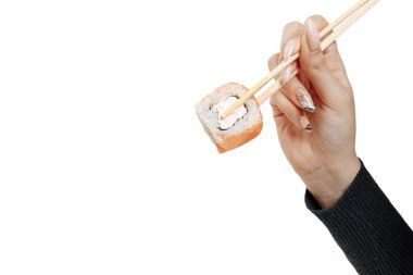 Somon, avokado krem peynir ve salatalık ile Philadelphia 'yı yuvarla. Çubuklu Japon suşisi. Bir El beyaz arka planda çubuklarla rulo tutuyor..