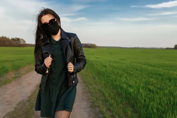 Dívka v lékařské masce běhá nebo kráčí po zeleném poli. Karanténní jaro. coronavirus. COVID 19. Virus chřipky, nachlazení — Stock fotografie