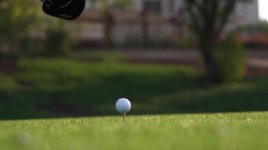 Golf sopası çok yavaş çekimde bir golf topuna vurur. Sabah çiy damlaları ve çim tanecikleri çarpışmadan sonra havaya yükselir.