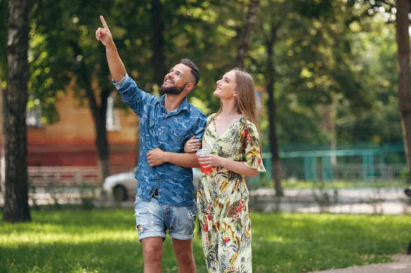 Belo jovem casal apaixonado andando no parque de verão com limonada fria. Casal romântico em uma data ao ar livre — Fotografia de Stock