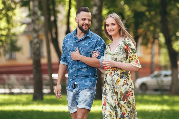 Belo jovem casal apaixonado andando no parque de verão com limonada fria. Casal romântico em uma data ao ar livre — Fotografia de Stock