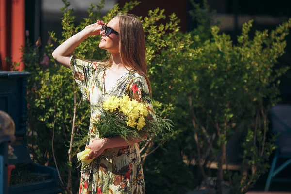 Stylová dívka pózuje v šatech ve slunném jarním parku. — Stock fotografie