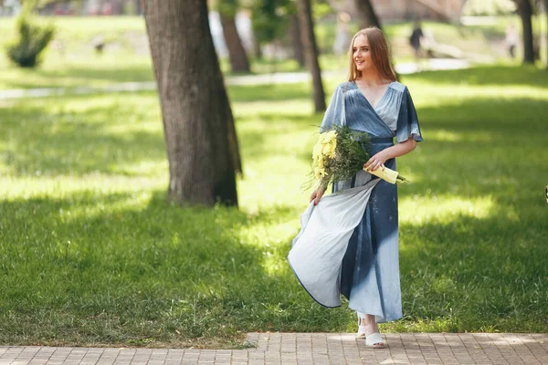 Стильная девушка позирует в платье в солнечном весеннем парке . — стоковое фото