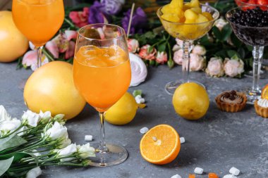 Büyük bardakta Aperol Spretz kokteyli, yaz aylarında İtalyan alkolsüz soğuk içeceği. Dekoratif bir arka planda, çilekli, turuncu ve dekoratif.