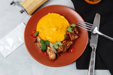 Beyaz tabakta ızgara tavuk şişi ve kabak püresi..