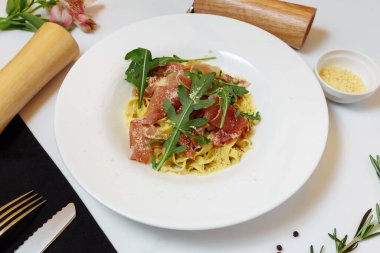 Lezzetli İtalyan makarnası aperatifi basturma ve taze fesleğen üzerine beyaz masa arkaplanı.