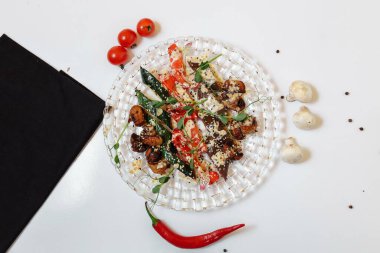 Hafif desenli arka planda cam bir tabakta ızgara sebzeler.