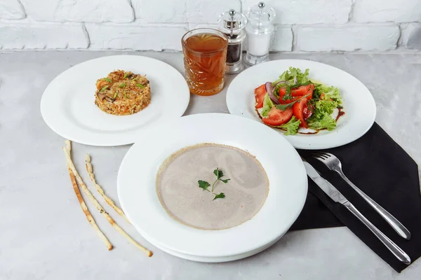 Zakelijke lunch van een bord met champignonroom soep, met kip en ei, een salade van verse groenten en pilaf — Stockfoto