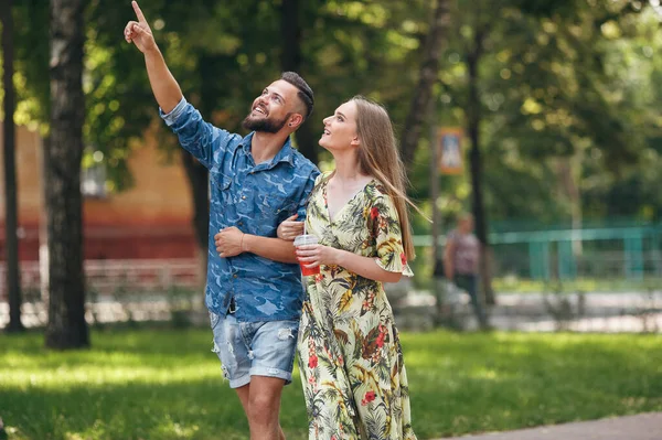 Belo jovem casal apaixonado andando no parque de verão com limonada fria. Casal romântico em uma data ao ar livre — Fotografia de Stock