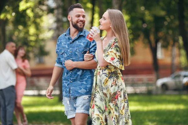 Belo jovem casal apaixonado andando no parque de verão com limonada fria. Casal romântico em uma data ao ar livre — Fotografia de Stock