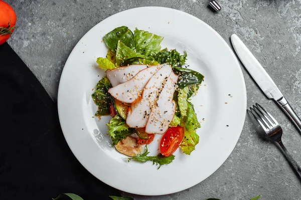 Sallad med kött, tomat, salladsströssel, krabba. Kycklingkött och tomater med gurka på en grå bakgrund. Livsmedel och livsmedelskoncept — Stockfoto