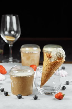 Açık arkaplanda waffle külahında dondurma. Dondurma eriyor. Waffle konileri ve çilekler arka planda.