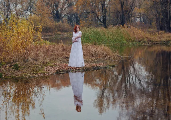 Young happy woman in a park near the river in autumn season — Stock Photo, Image