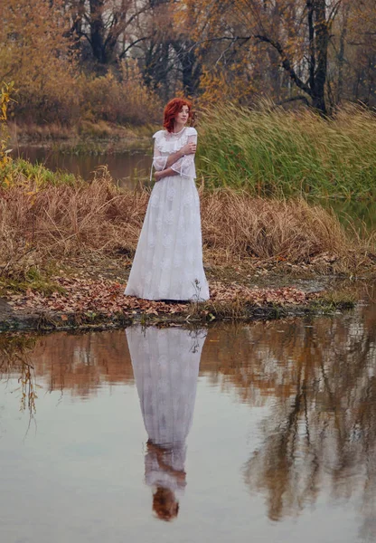 Gelukkig jongedame in een park in de buurt van de rivier in de herfst seizoen Stockfoto