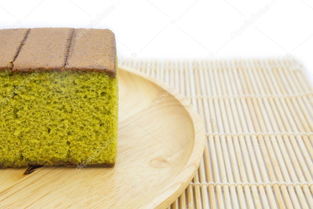 Japanese Matcha green tea cake cheesecake on wooden plate and traditional mat isolated white background. copy space