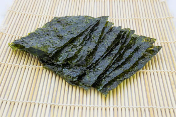 Закуска из жареных морских водорослей (kim nori) на традиционном бамбуковом коврике — стоковое фото