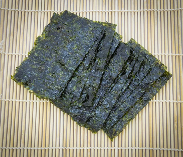 Closeup roasted seaweed snack (kim nori) on traditional bamboo mat — Stock Photo, Image