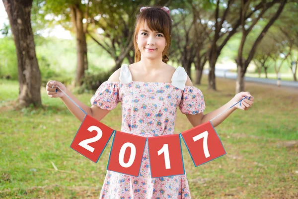 Sonrisa de la mujer linda mano sosteniendo el signo de papel 2017, feliz año nuevo —  Fotos de Stock