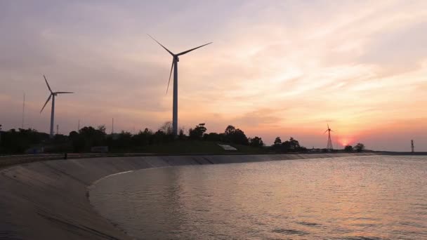 Windturbines maken groene energie met reservoir bij zonsondergang — Stockvideo