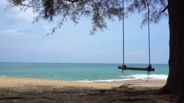 Ultrahd ビデオ 小さな波はそっとこれを平和に洗ってください タイのプーケットで熱帯のビーチ 青い空を背景に水の近くの木からロープ スイングがハングアップします — ストック動画